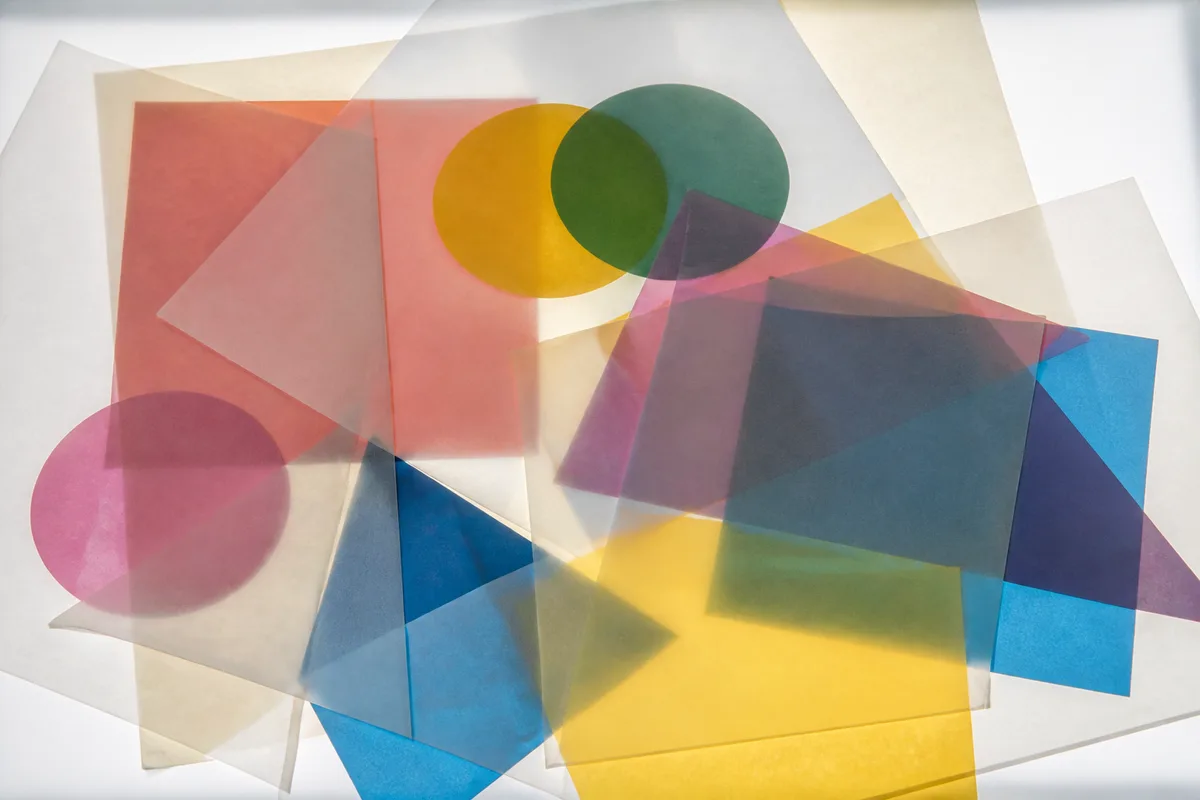 Feuilles de papier calque superposées sur des formes géométriques colorées éclairées par une table lumineuse